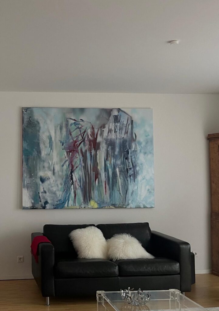 Großformatiges Kunstwerk über einem schwarzen Sofa in einem privaten Wohnraum